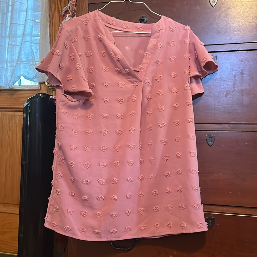 V-necked pale purple top decorated wit Pom Poms and a ruffled sleeve